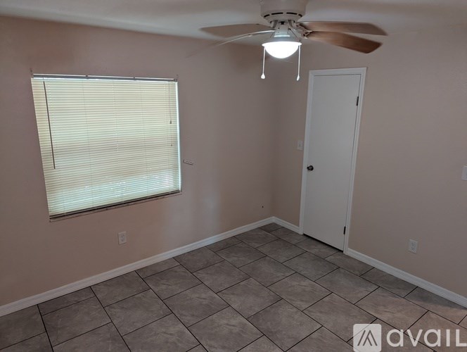 A room with a ceiling fan, a window with blinds, and a door.