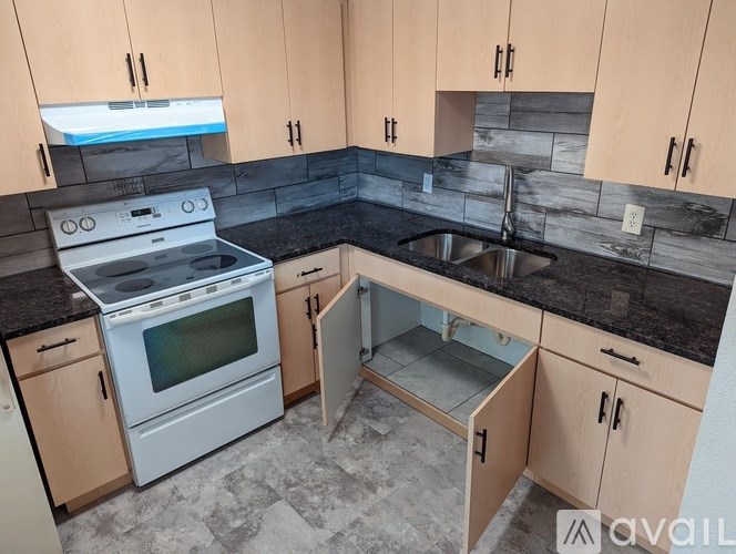 A kitchen with a stove, sink, and cabinets.