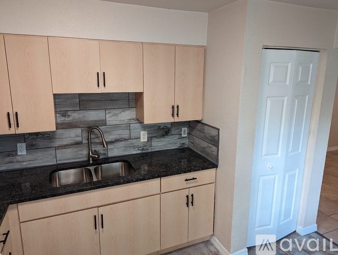 A kitchen with wooden cabinets and a black countertop.