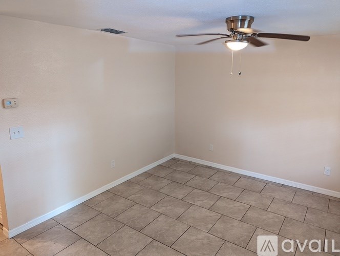 A room with a ceiling fan and light fixture, and a tiled floor.