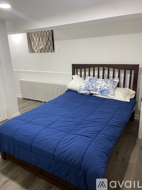 A bed with a blue comforter and a pillow with a blue and white pattern.