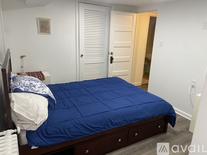 A bedroom with a bed, nightstand, and a window with blinds.