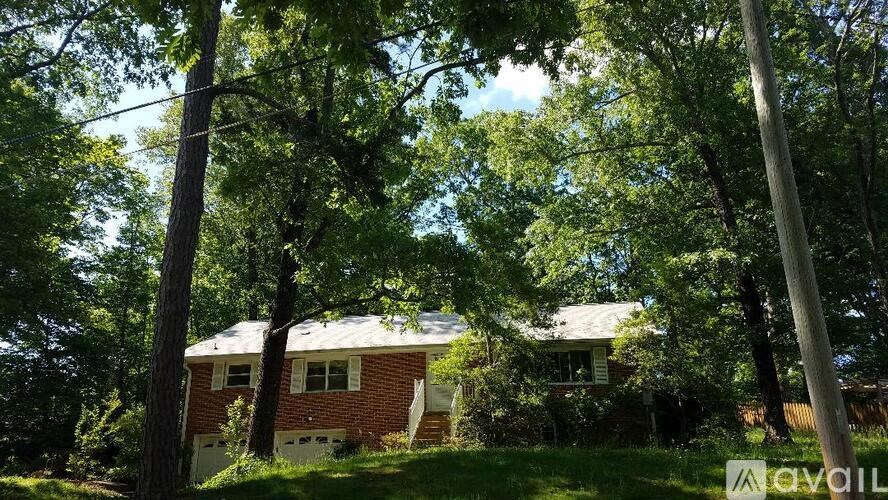 A house with a red brick exterior is surrounded by trees.