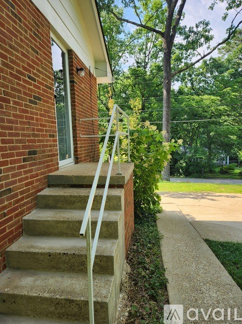 A set of stairs with a white railing lead up to a door on a brick house.