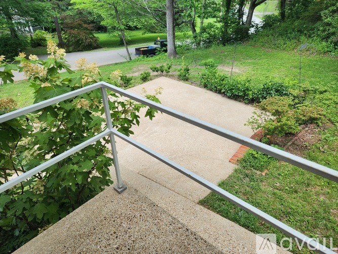 A concrete staircase with a metal railing leads down to a grassy area.