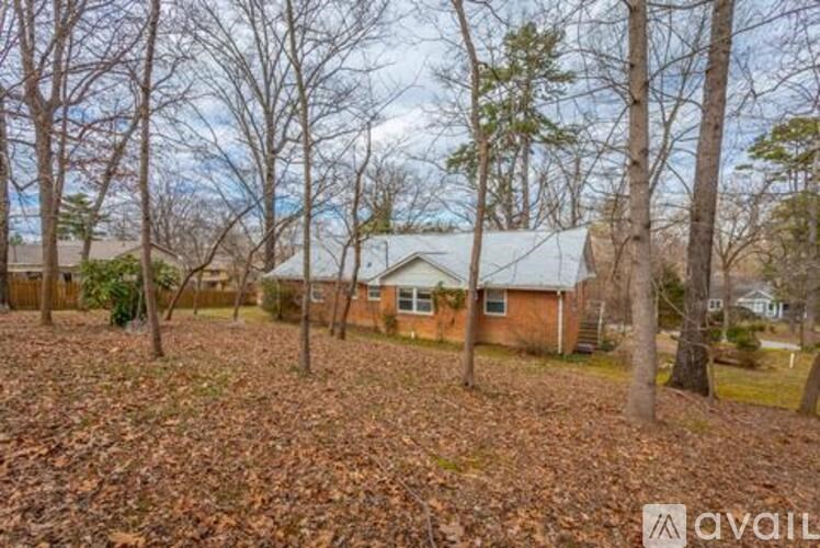 A house surrounded by trees with a carpet of leaves on the ground.