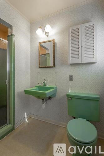 A bathroom with green toilet and sink.