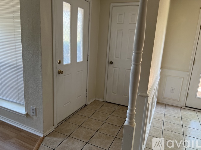 A hallway with a white door and a tiled floor.