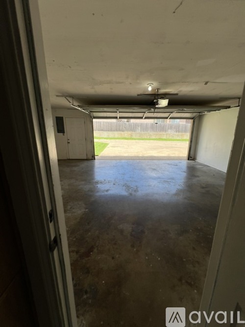 A large empty room with a concrete floor and a door leading to a grassy area.