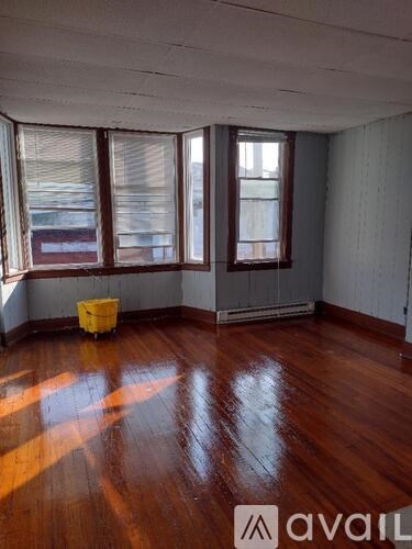 A room with wooden floors and a yellow bucket.