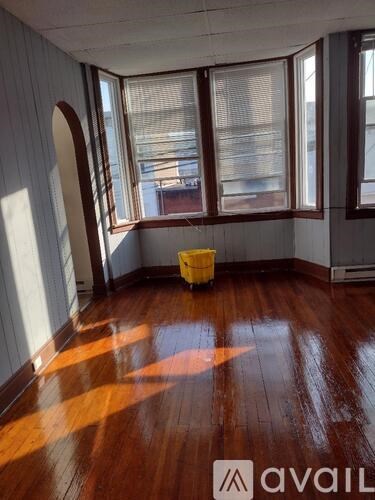 A room with wooden floors and a window with a view of a building outside.