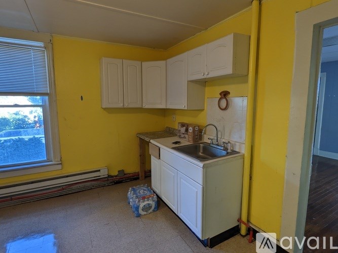 A kitchen with yellow walls and white cabinets.