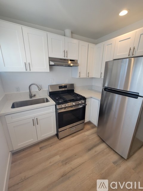 A kitchen with white cabinets and a stainless steel refrigerator.