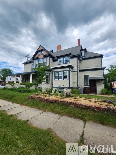 A two-story house with a large front yard and a sidewalk leading to the front door.