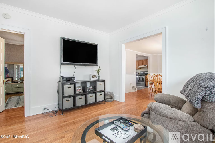 A living room with a television, a glass coffee table, and a grey sofa.