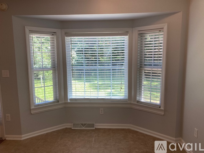 A room with two windows and a view of a fence and trees outside.
