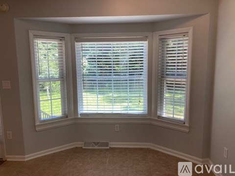 A room with two windows and a view of a fence and trees outside.