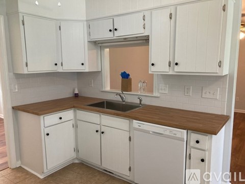 A kitchen with white cabinets and a wooden countertop.