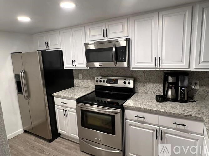 A kitchen with black appliances and white cabinets.