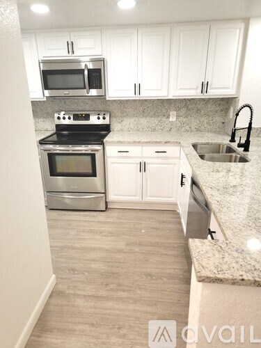 A kitchen with white cabinets and a granite countertop.