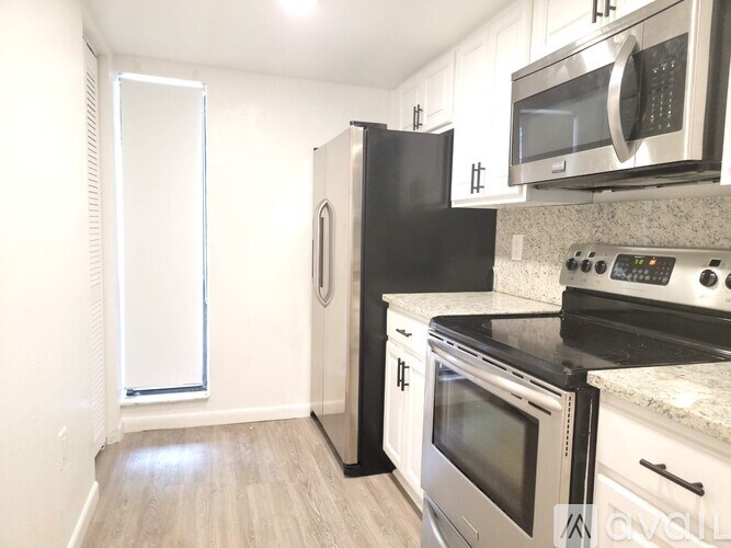A kitchen with black and white appliances and a window.