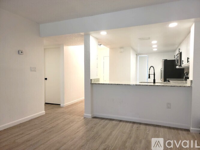 A spacious, empty room with a bar area and a television.