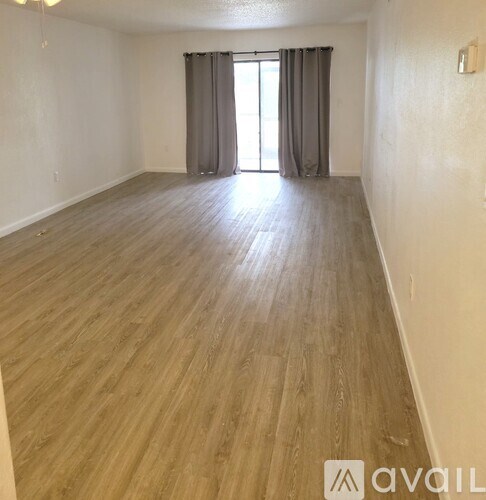 A room with wooden flooring and a window with curtains.