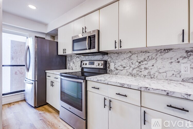 A kitchen with a marble countertop and stainless steel appliances.