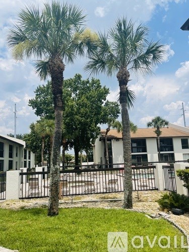 Two palm trees in front of a white building with a black fence.