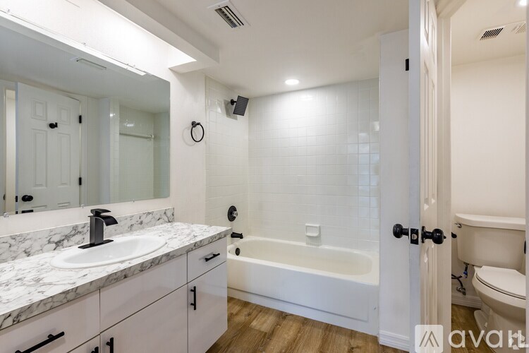 A bathroom with a marble countertop and a white bathtub.