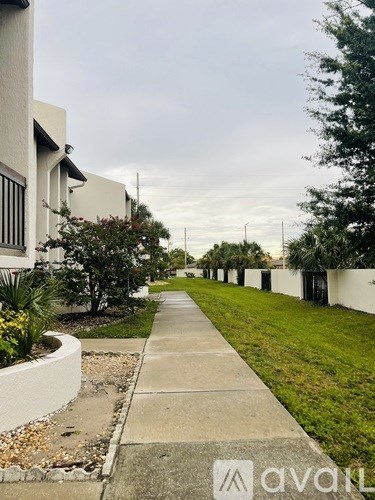 A sidewalk runs down the middle of a quiet street lined with white houses.