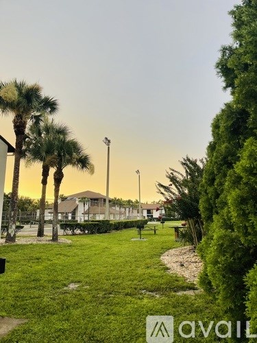 A park with palm trees and a building in the background.