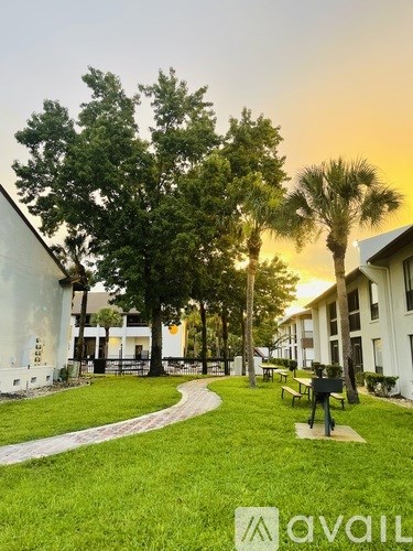 A grassy area with benches and trees in front of a building.