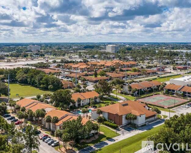 A bird's eye view of a residential area with multiple houses and a tennis court.