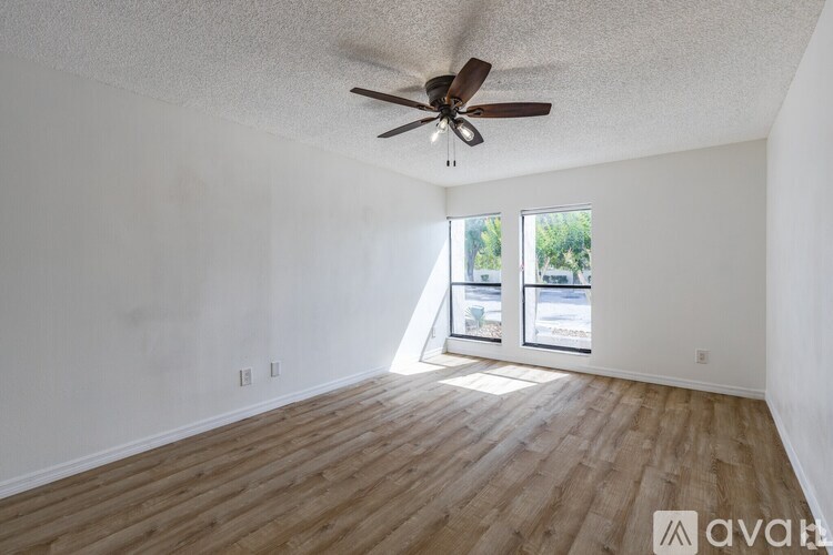 A room with a ceiling fan and wooden flooring.