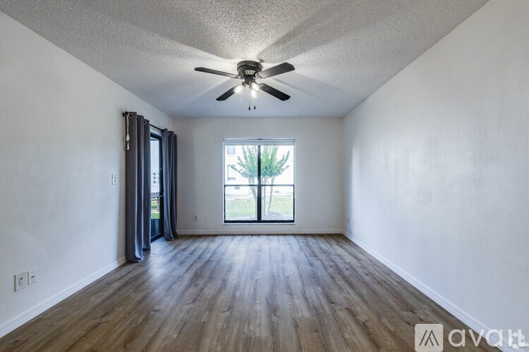 A room with a ceiling fan and wooden flooring.