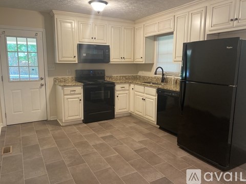 A kitchen with black appliances and white cabinets.