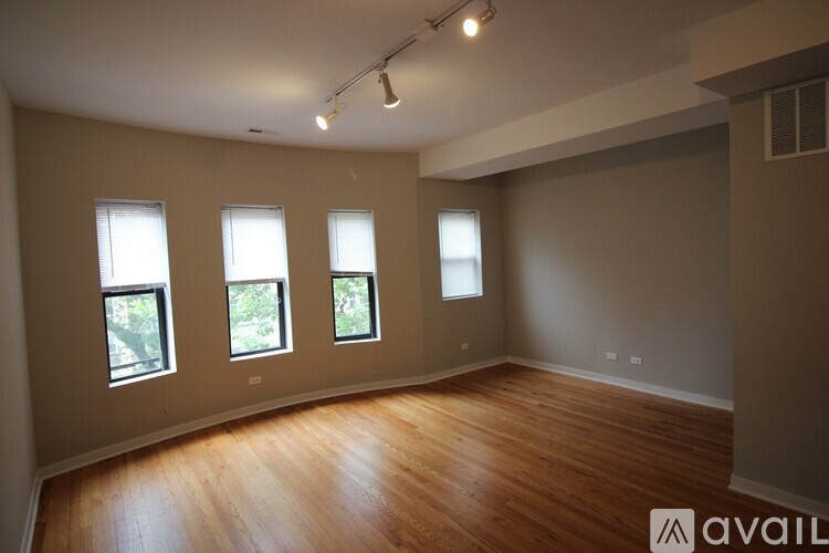 A room with wooden floors and four windows.