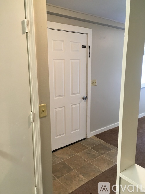 A white door is in a hallway with a tiled floor.