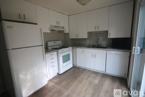 A kitchen with white appliances and cabinets.