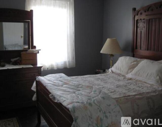 A bedroom with a bed, a dresser, and a lamp.