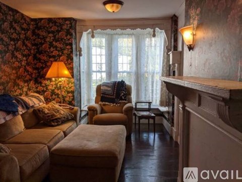 A living room with a couch, ottoman, and a fireplace.