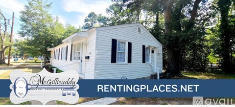 A white mobile home is for rent in a wooded area.