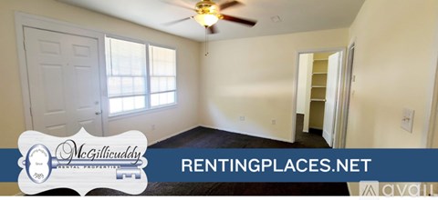 A spacious room with a ceiling fan and a door leading to another room.