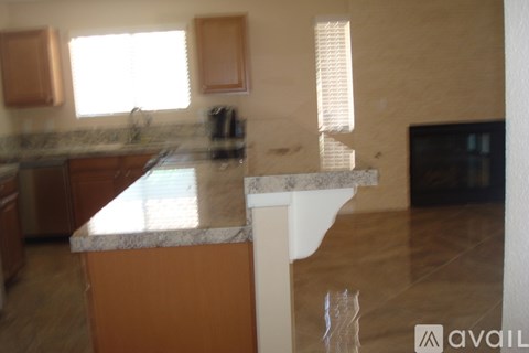 A kitchen with a granite counter top and wooden cabinets.