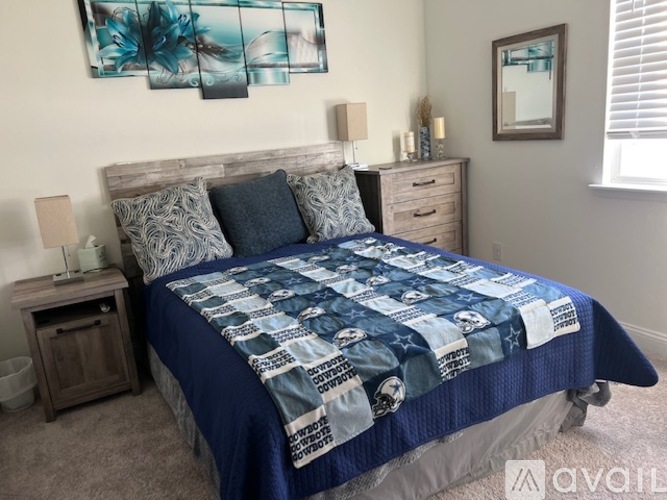 A bed with a blue comforter and pillows in a bedroom.