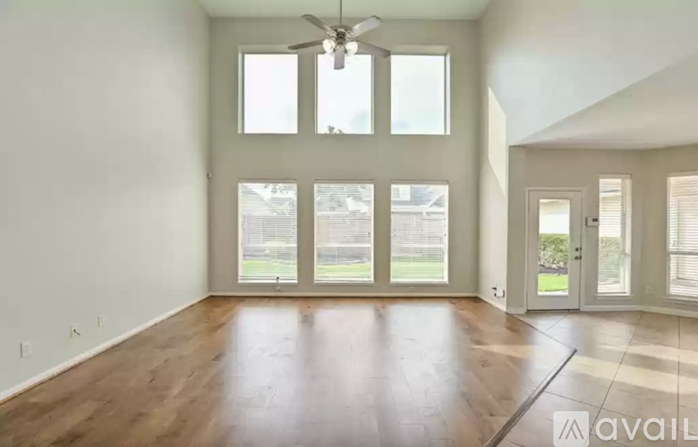 A spacious room with a ceiling fan and large windows.