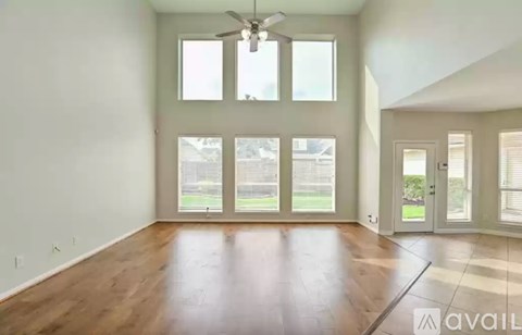A spacious room with a ceiling fan and large windows.