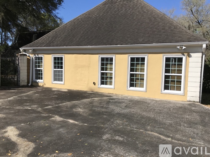 A yellow house with a black roof and a white garage door.