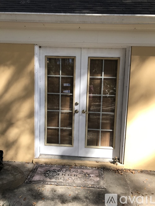 A white double door with a glass panel and sidelights is set in a white frame with a small window above the right door.